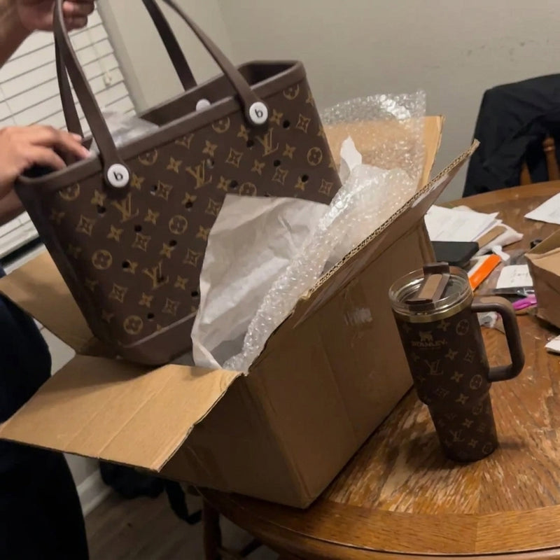 Brown tote pulled from the box with matching tumbler on a wood table