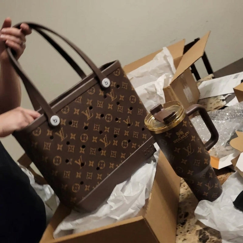 Hands holding a brown tote with matching brown tumbler on the box
