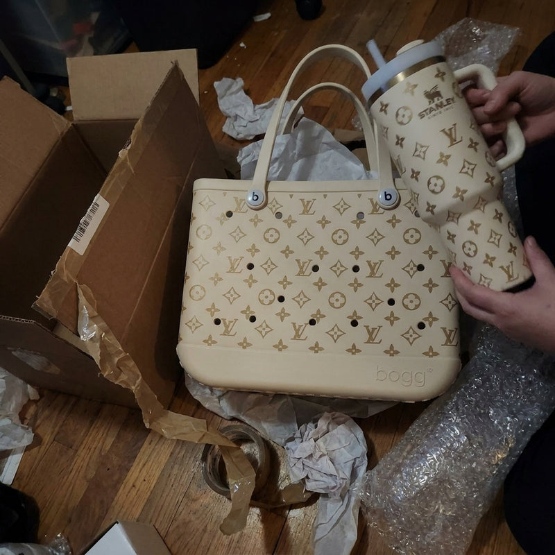 Hands holding a cream tumbler with the matching tote on the floor