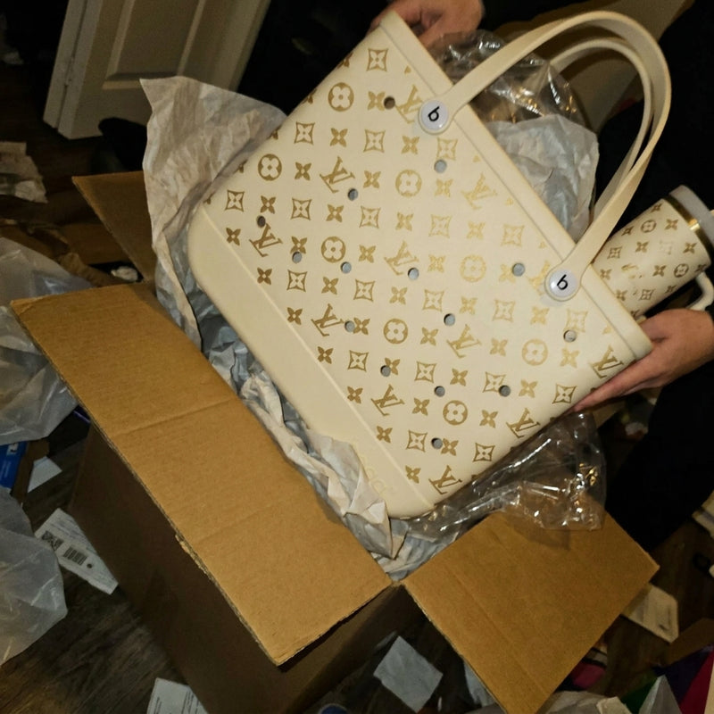 Hands lifting a cream tote with the tumbler tucked inside